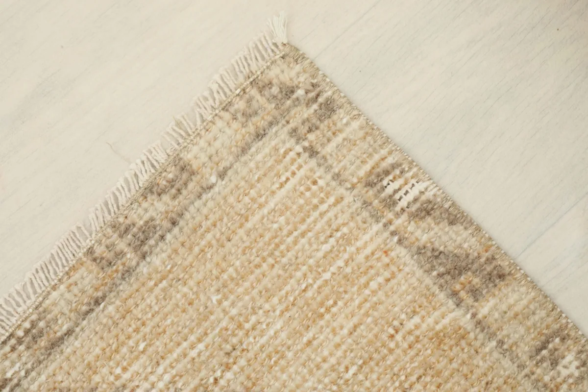 Corner detail of the rug showing the woven fringe and the muted border design.