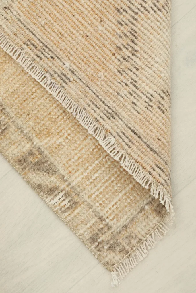 View of the rug folded at a corner, revealing the cotton foundation and back weave.