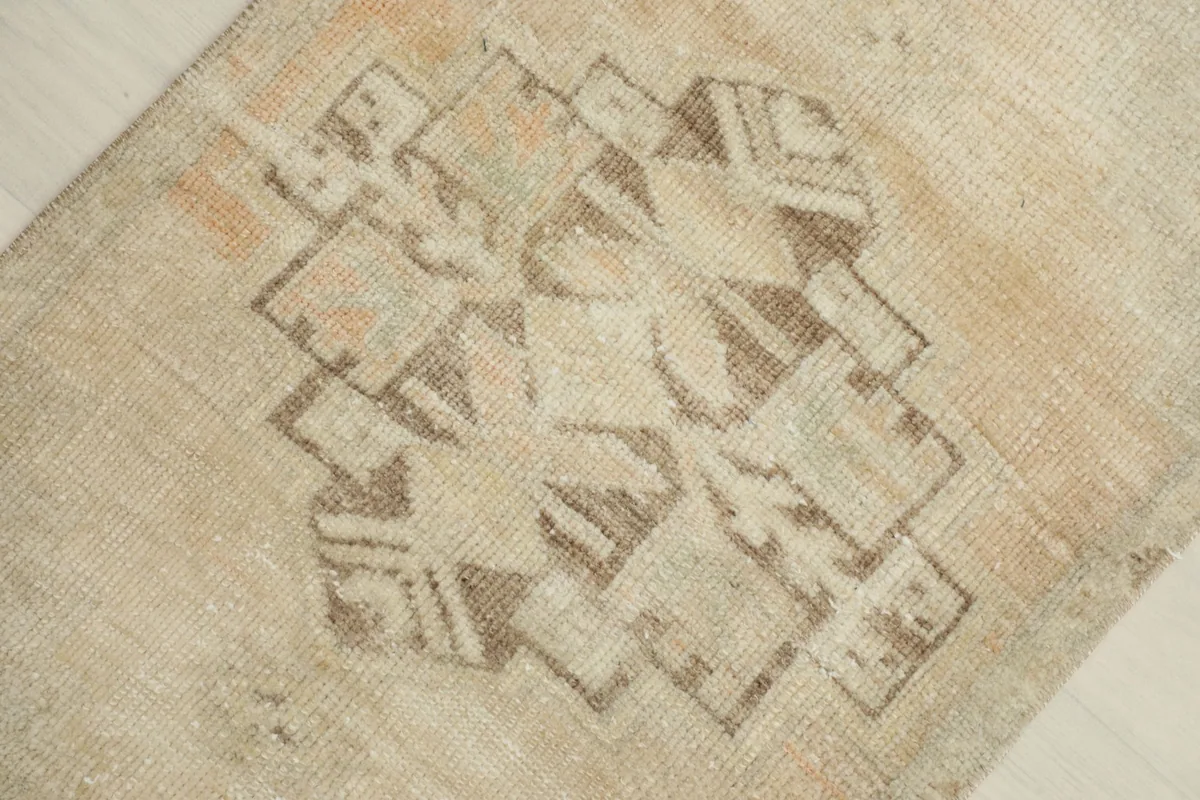 Detailed view of the central brown and tan geometric motif on the cream rug