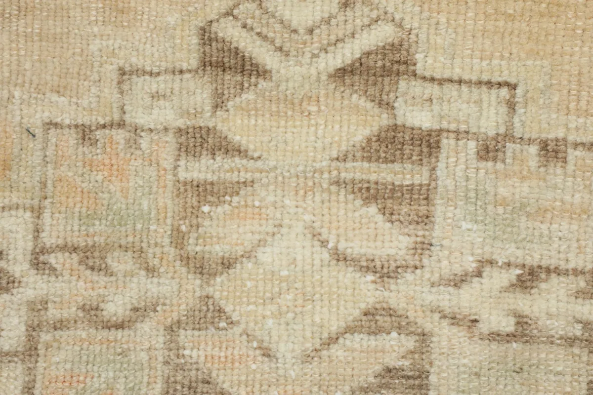 Close-up of the hand-knotted wool texture and faded geometric pattern