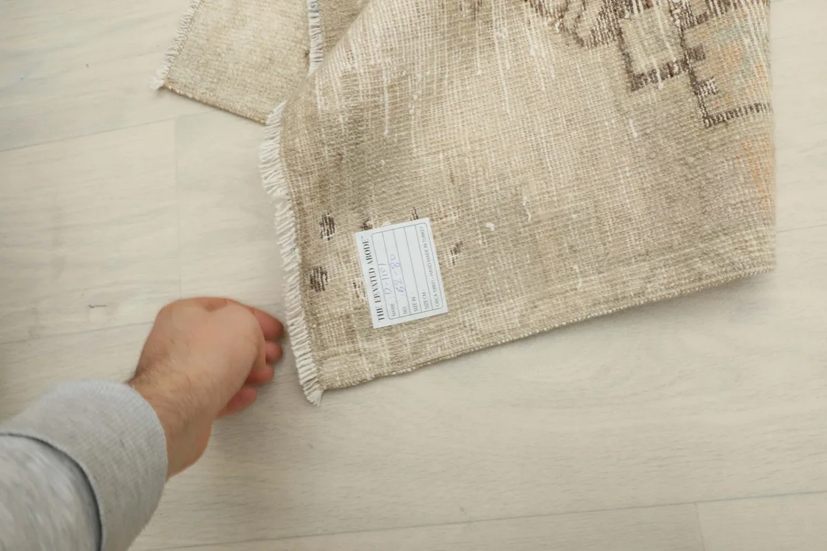 Hand touching the rug to indicate its size and texture