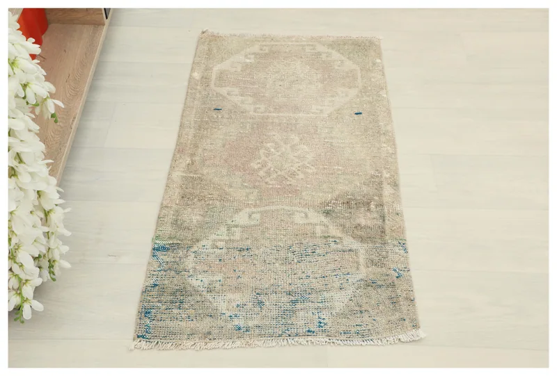 Full top view of the 1'8" x 3'1" beige and blue vintage Anatolian area rug on a white floor.