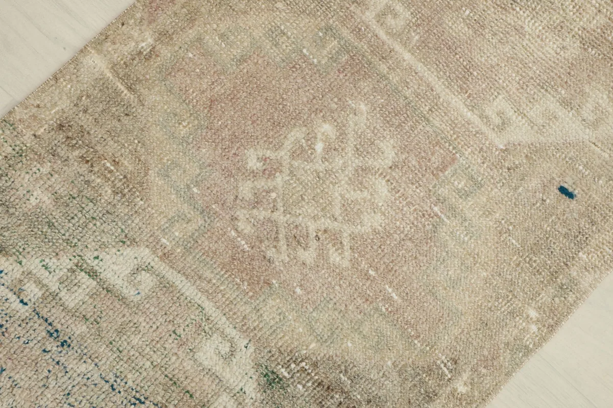 Detailed view of the central geometric motif and faded rose and beige colors in the rug's pattern.