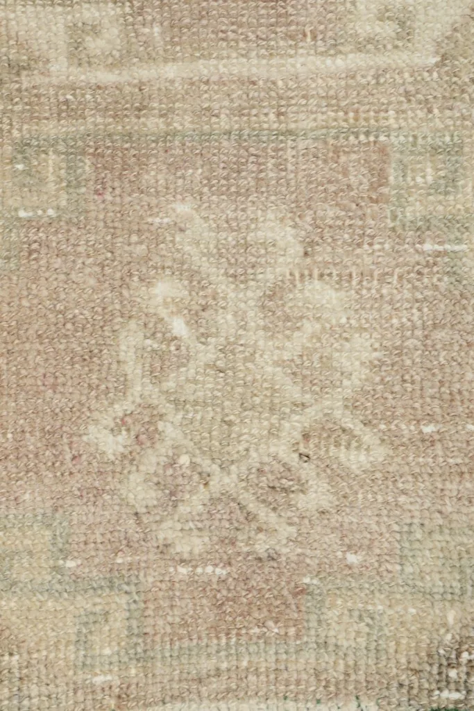 Close-up of a distinct geometric pattern and subtle color variations within the vintage rug.