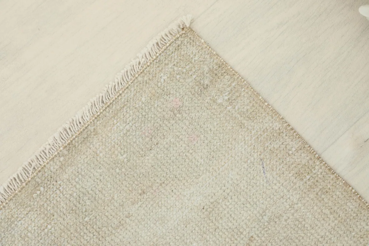 Angled view of a corner of the ivory doormat, highlighting its vintage texture.
