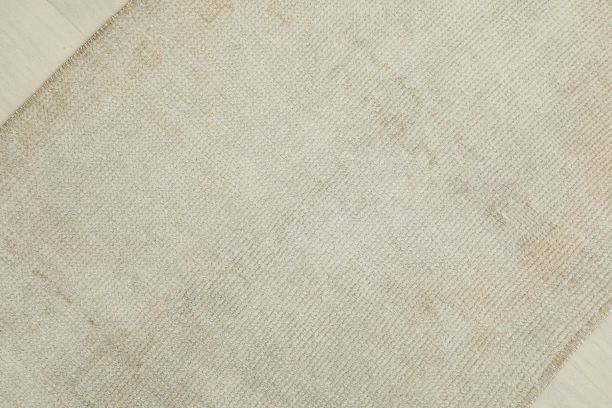 Angled close-up of the subtle texture and color variations on the ivory rug's surface.
