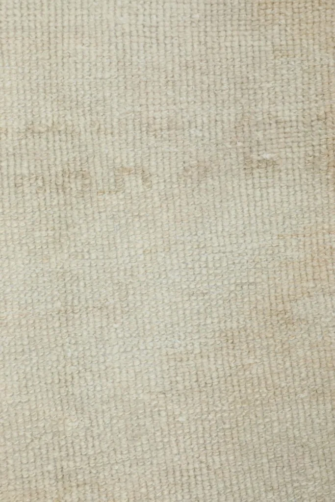Detailed view of the low wool pile and weave structure of the vintage ivory rug.