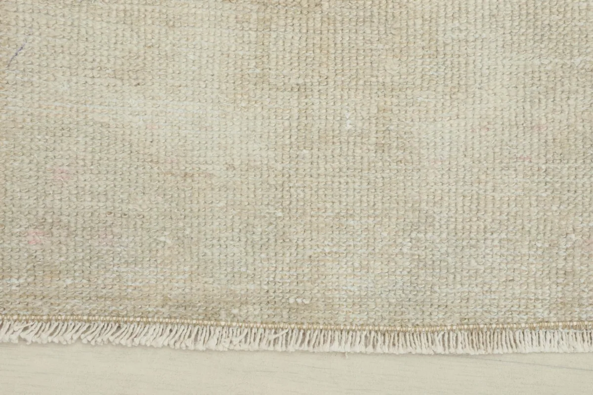 Close-up detail of the fringe and edge of the hand-knotted ivory wool doormat.