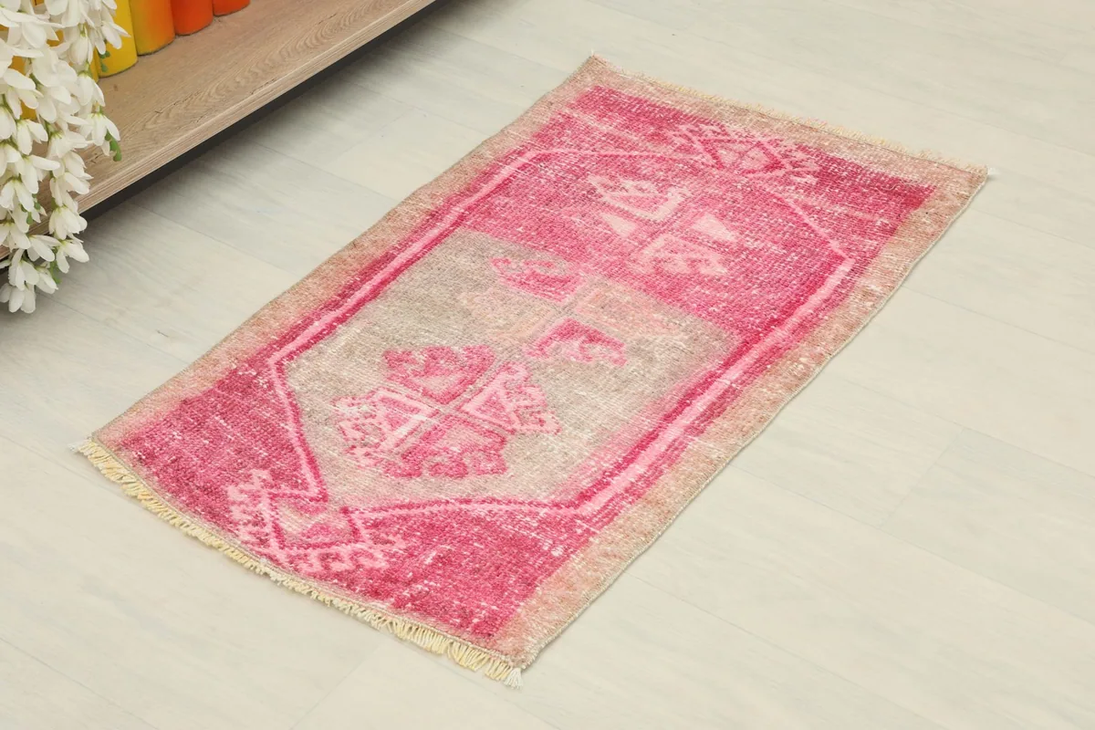 Angled view of the rose and beige hand-knotted wool rug