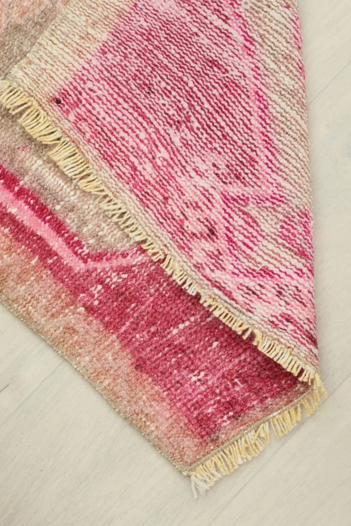 Folded corner of the rug revealing the wool pile and cotton foundation