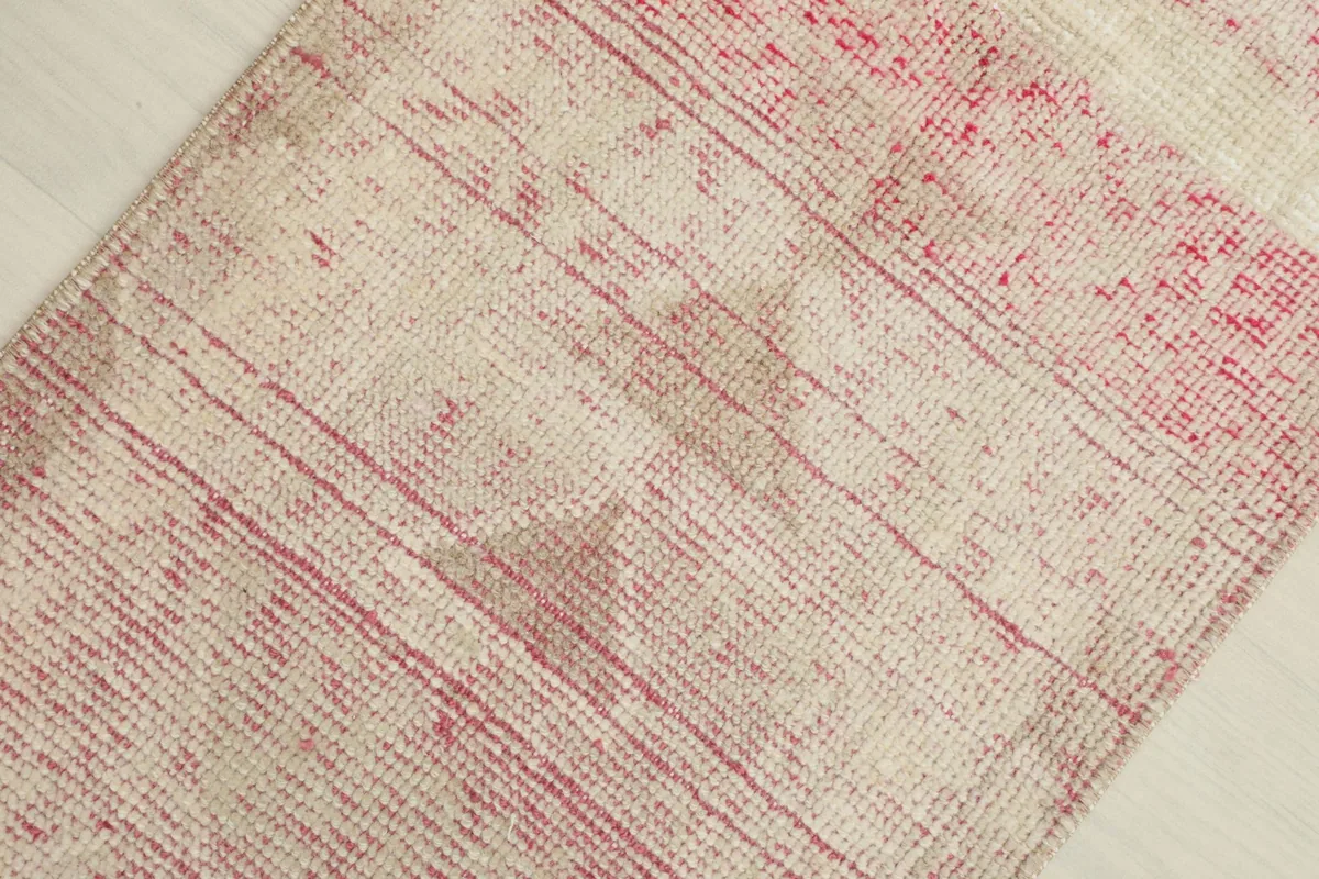 Detailed view of the faded rose stripes and ivory field, highlighting the hand-knotted texture.