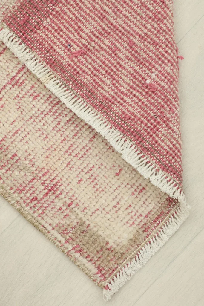 View of the rug folded to reveal the thickness and the back of the hand-knotted wool on cotton foundation.