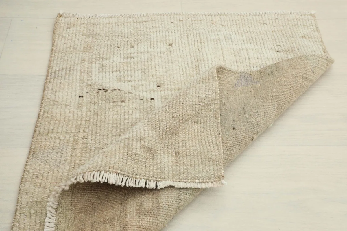 Partial view of the back of the rug, revealing the cotton foundation and knotting