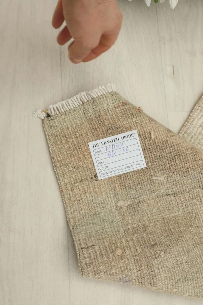 Close-up of the rug's back, showing the label with dimensions and origin