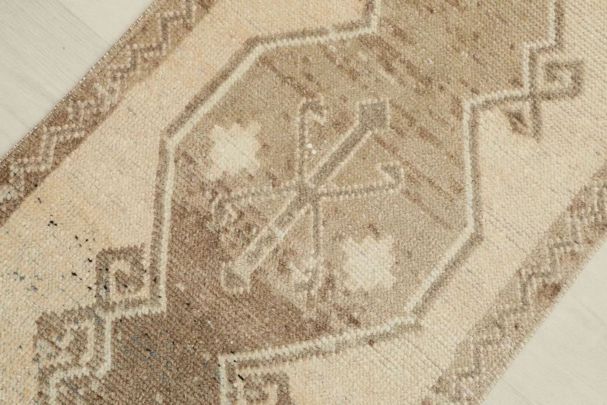 Close-up of the central geometric motif in brown and beige on the vintage rug