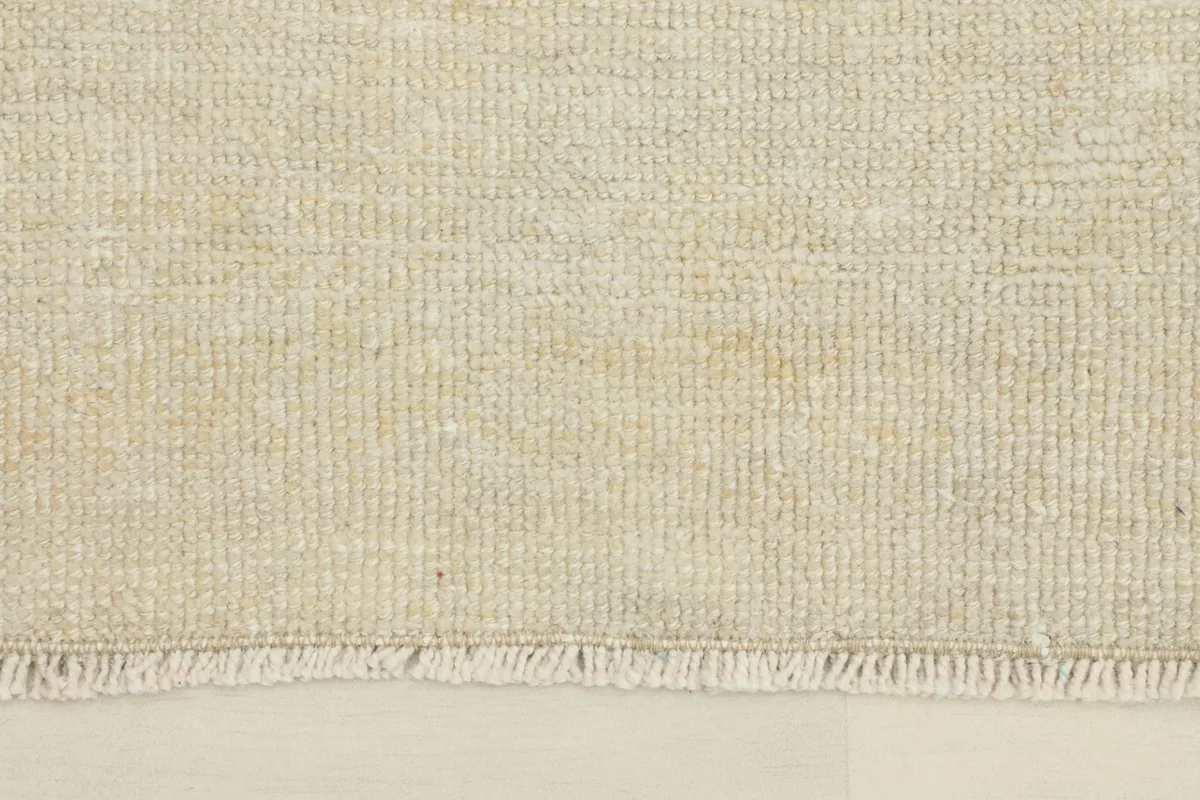 Close-up view of the low pile texture and subtle color variations of the cream rug