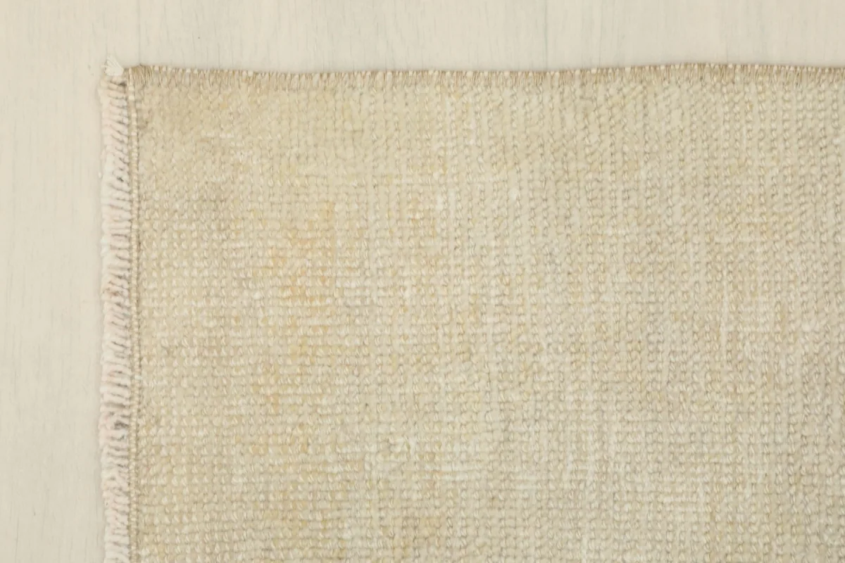 Corner detail of the cream rug showing the fringe and weave