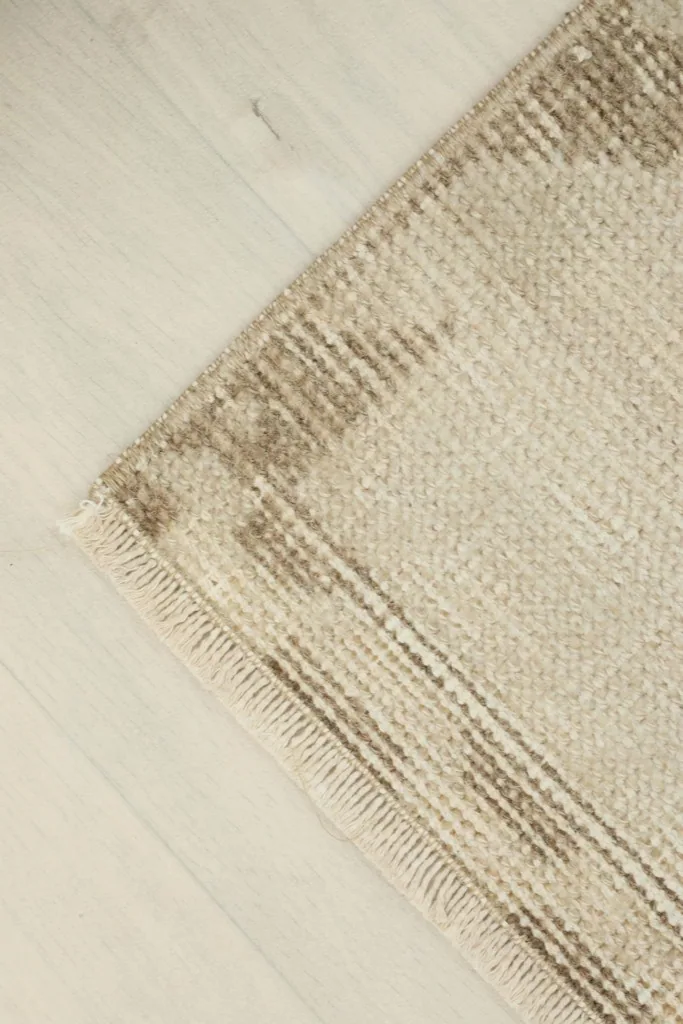 Angled view of the rug's corner, showing the texture of the low pile and subtle color variations.