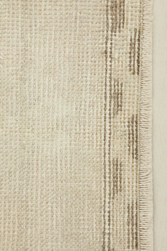 Close-up detail of the rug's edge, showing the hand-knotted wool pile and cotton foundation.