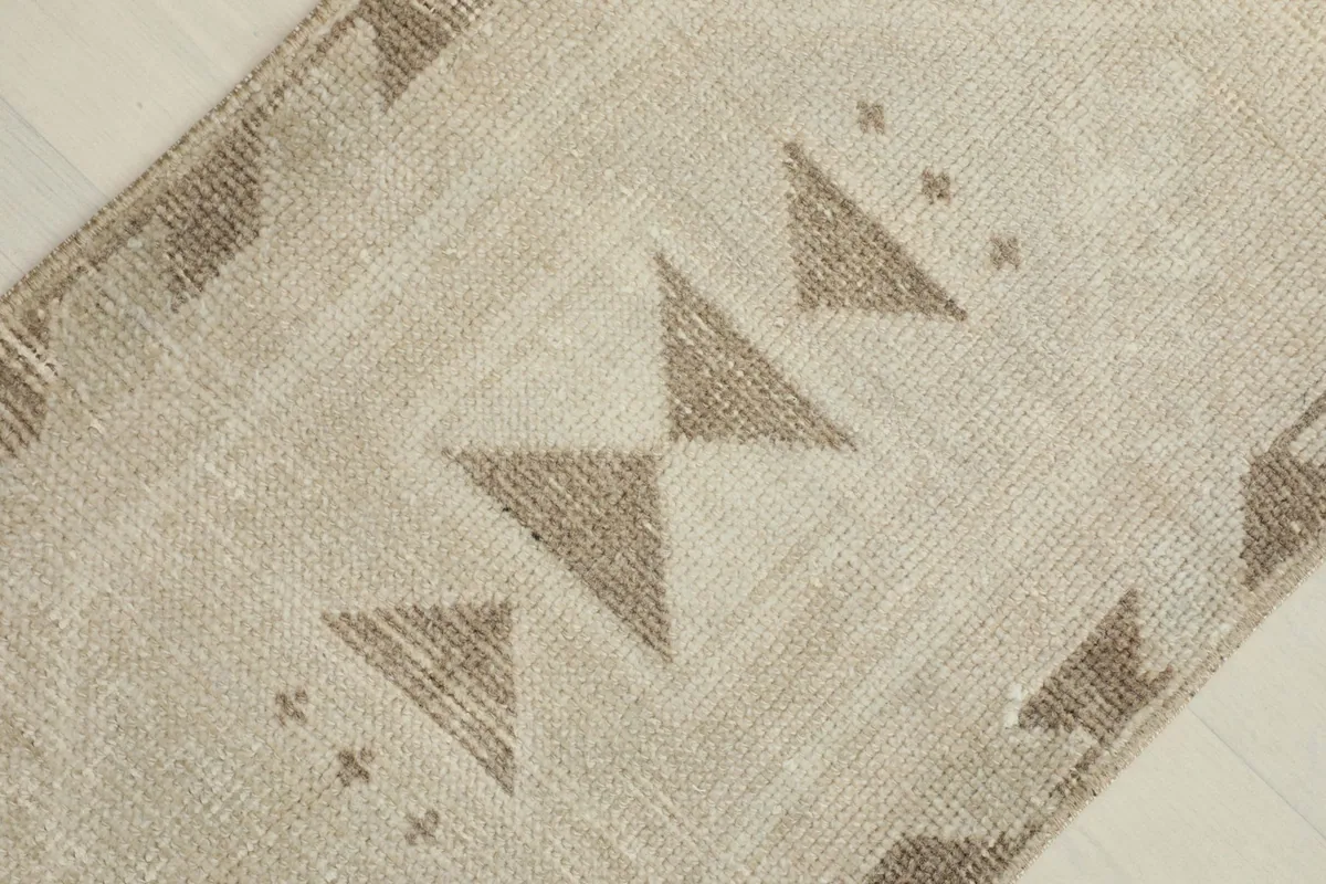 Close-up of the central tan geometric triangle motifs against the ivory field of the rug.