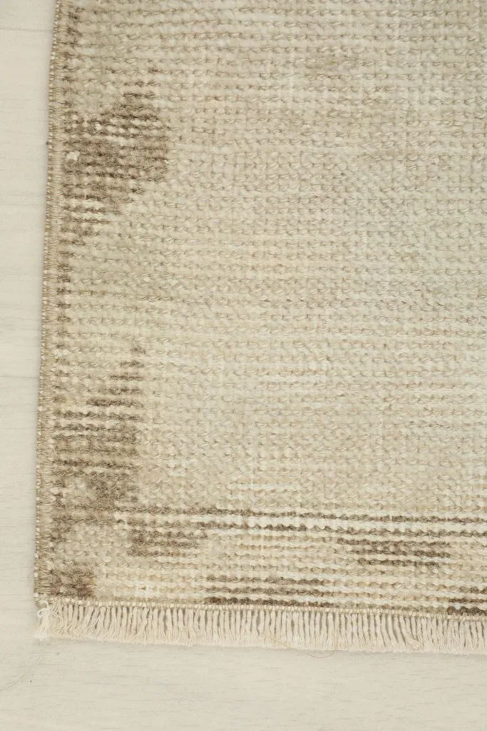 Close-up of a corner of the rug, highlighting the tan geometric border design and fringe.