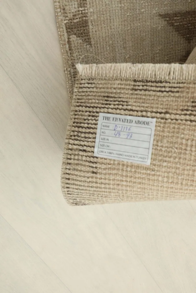 Underside of the rug with a product label visible, showing the hand-knotted weave.