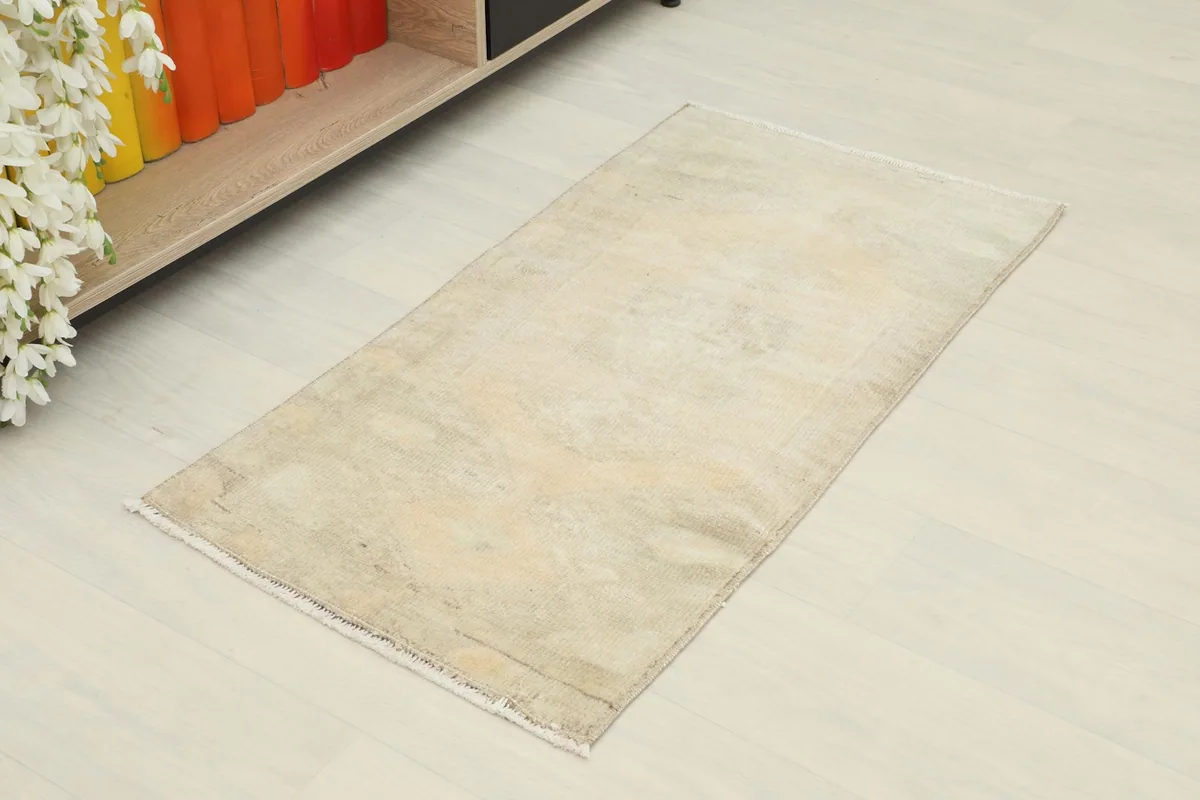 Vintage beige and tan hand-knotted rug from an elevated angle, showing its distressed surface
