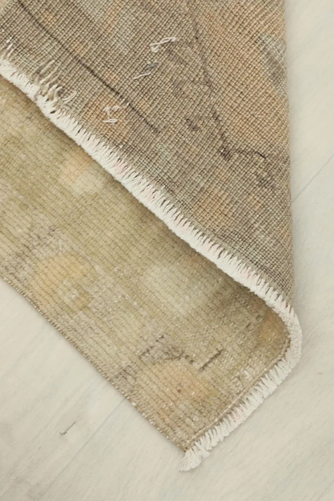 Rug folded at a corner to show the thickness of the wool pile and cotton foundation