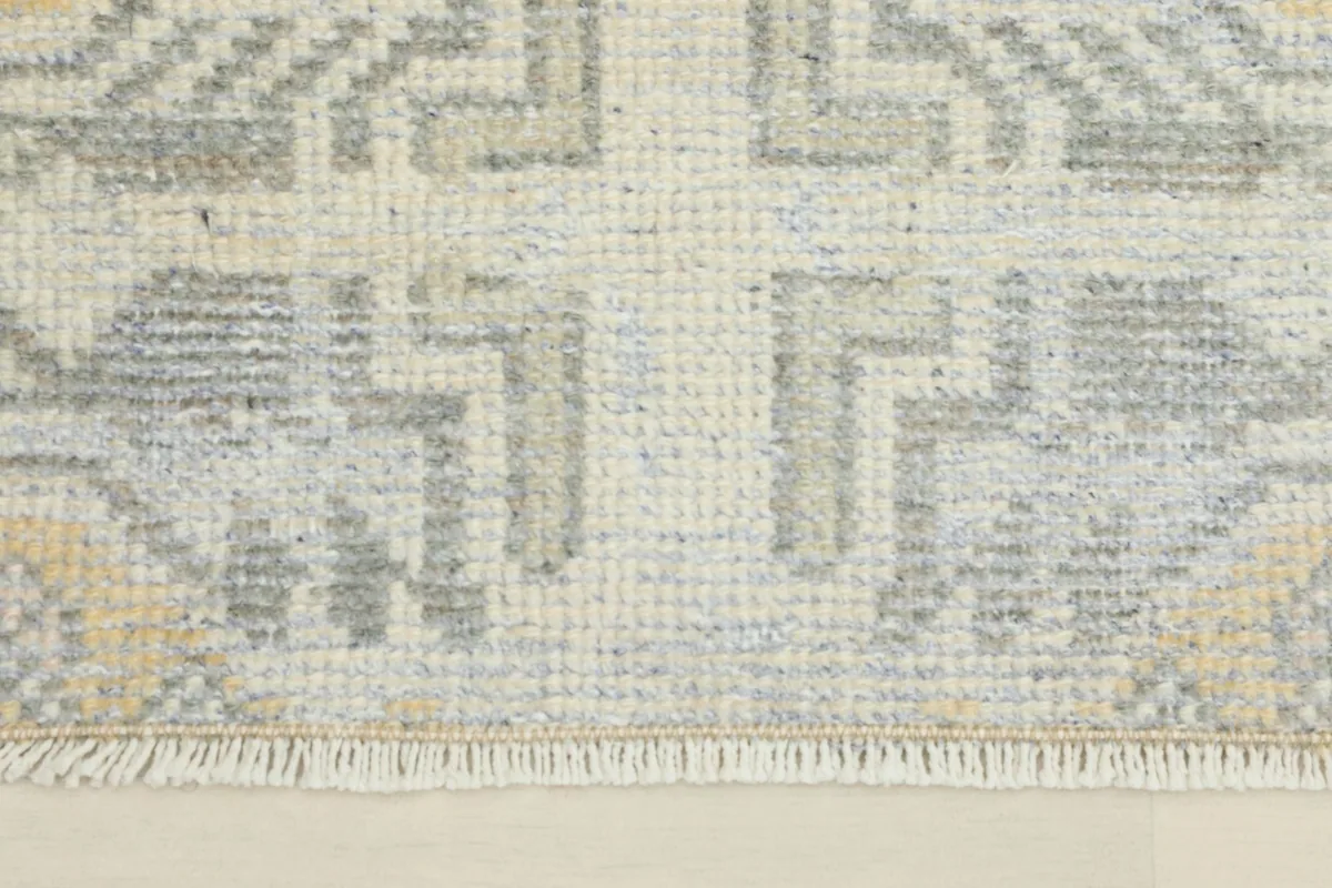 Close-up detail of the ivory field and gray geometric elements, revealing the wool pile texture.