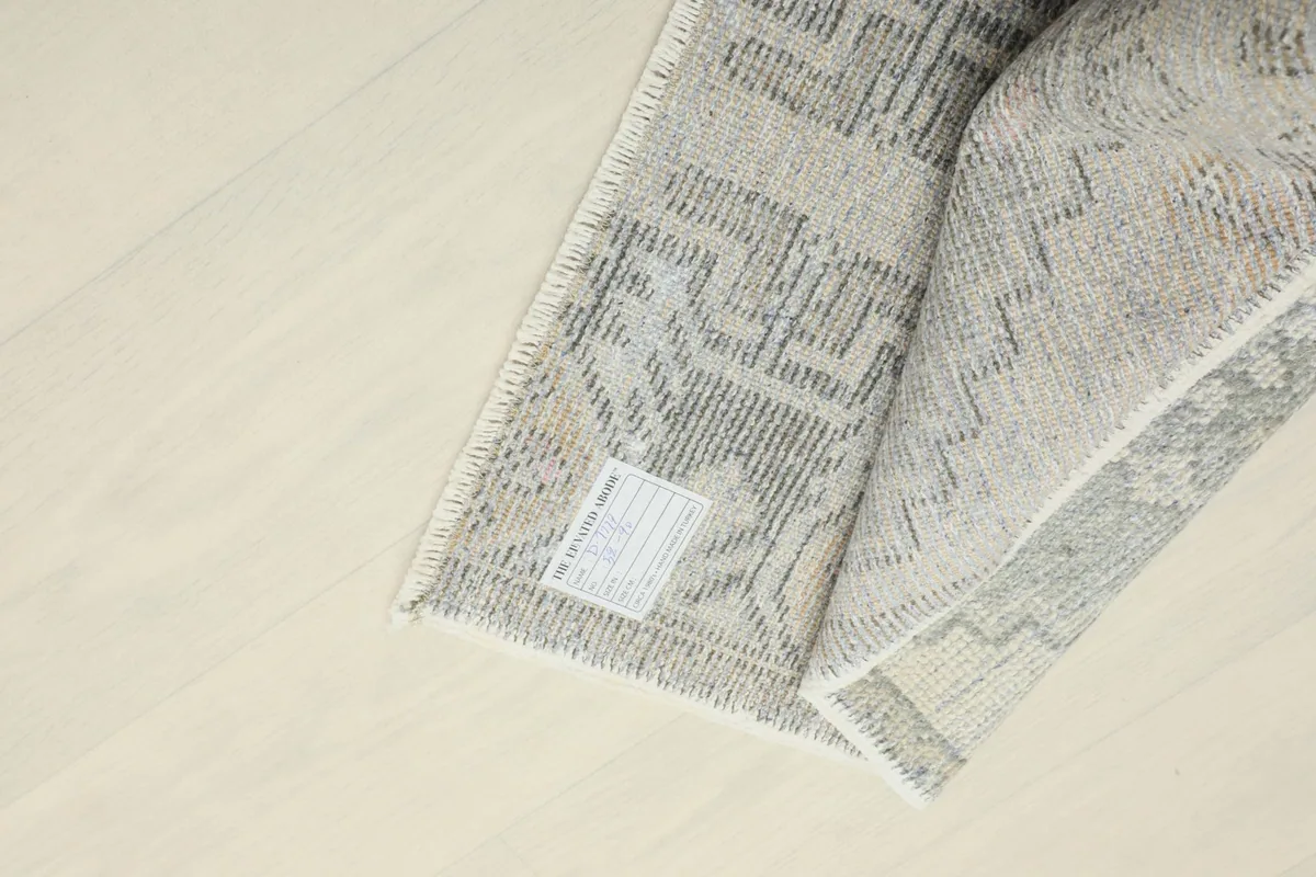 View of the back of the rug, revealing the tight knotting of the wool pile on a cotton foundation.