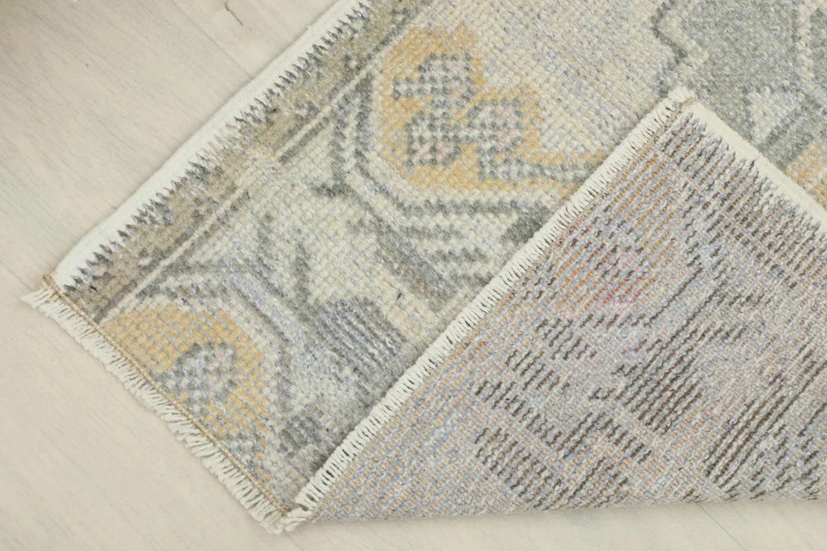 Partial fold of the rug, showing the reverse side and the hand-knotted construction.