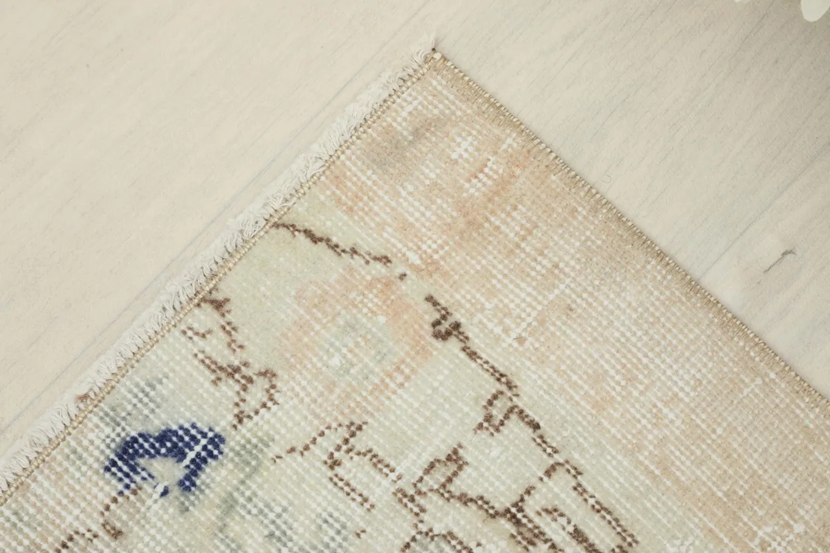 Corner view of the rug, illustrating the overall distressed appearance and the soft color transitions