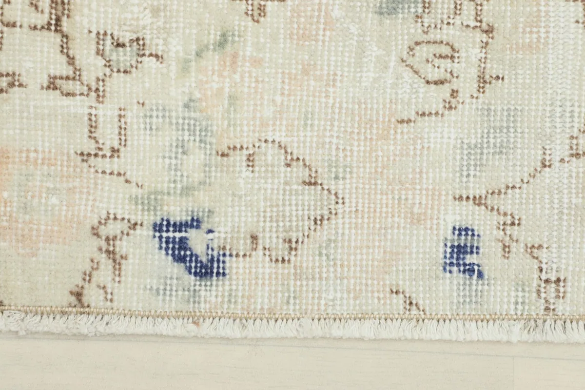 Close-up detail of the rug's faded floral motif and texture, highlighting the blue and brown accents