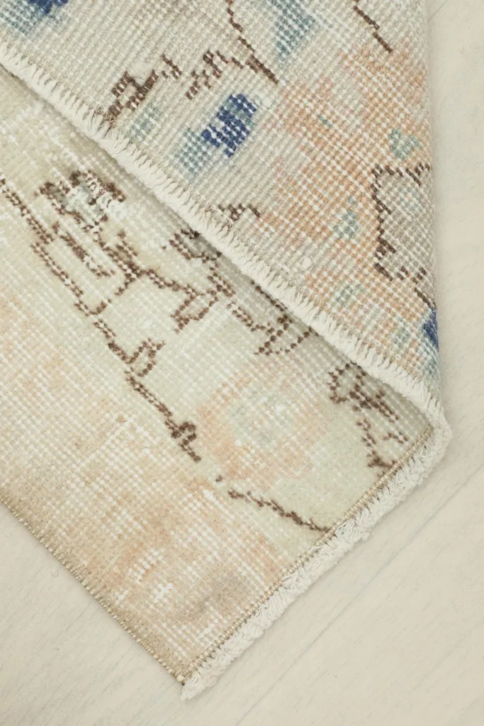 View of a folded corner of the rug, showing the reverse side and the hand-knotted cotton foundation