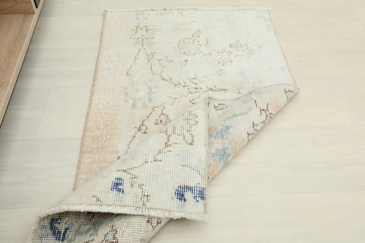 The rug with a section folded back, providing a perspective of its thickness and vintage condition