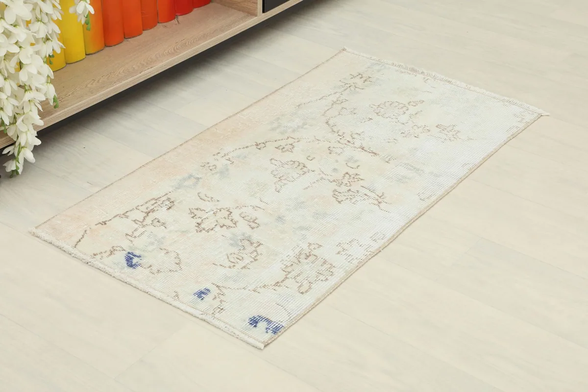 Slightly angled overhead view of the small ivory rug, showing its rectangular shape and soft colors