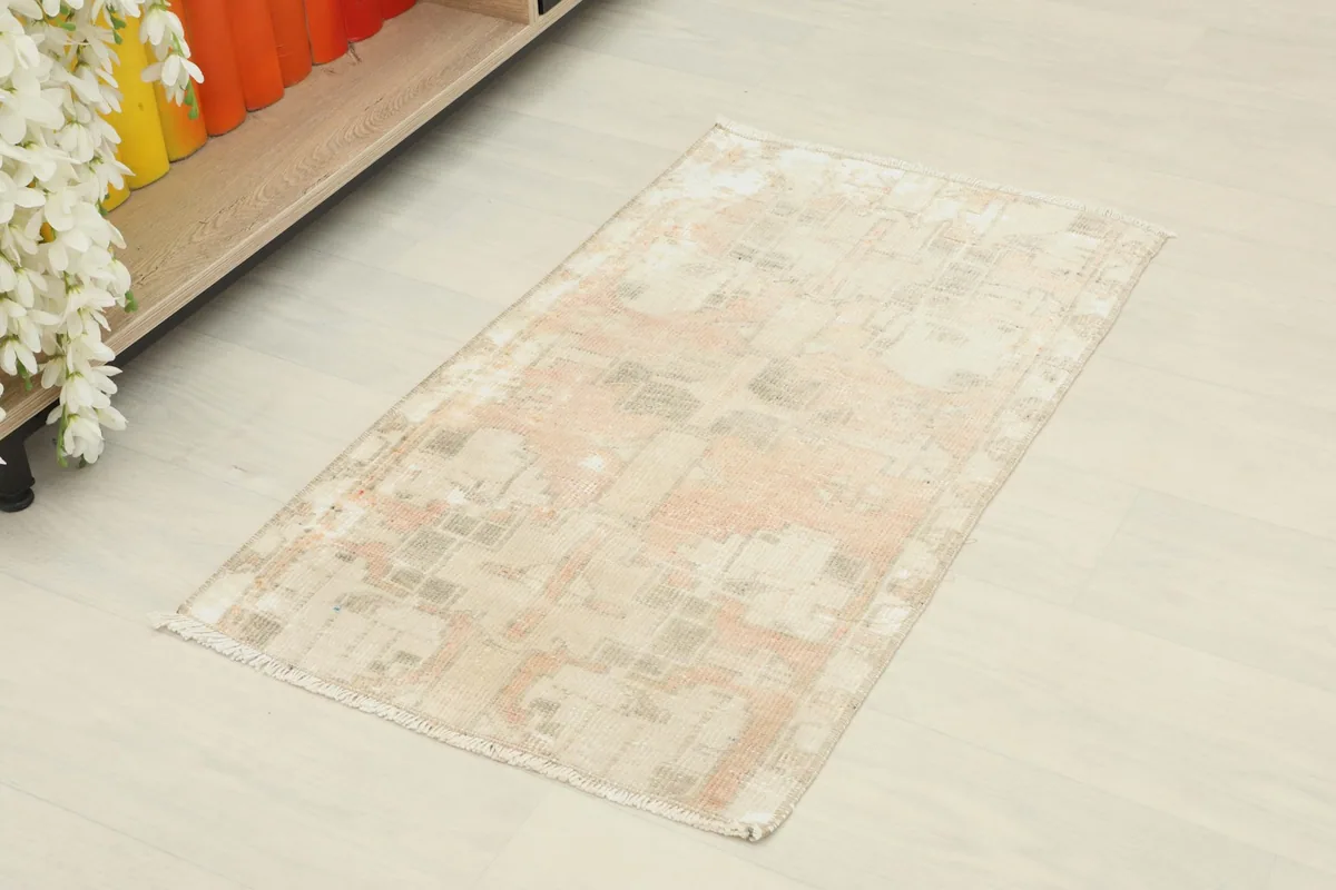 Angled view of the beige and rust vintage doormat on a light floor, showing its full length