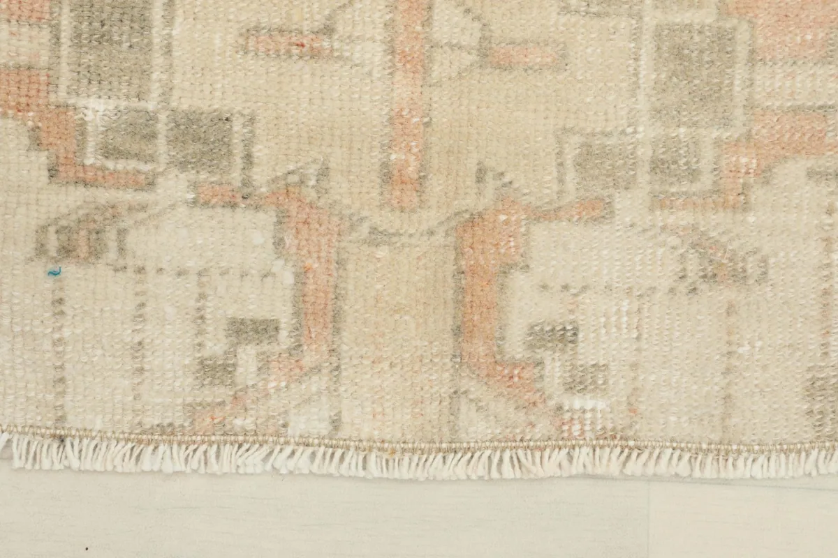 Close-up detail of the doormat's fringe and geometric pattern with beige, rust, and gray tones