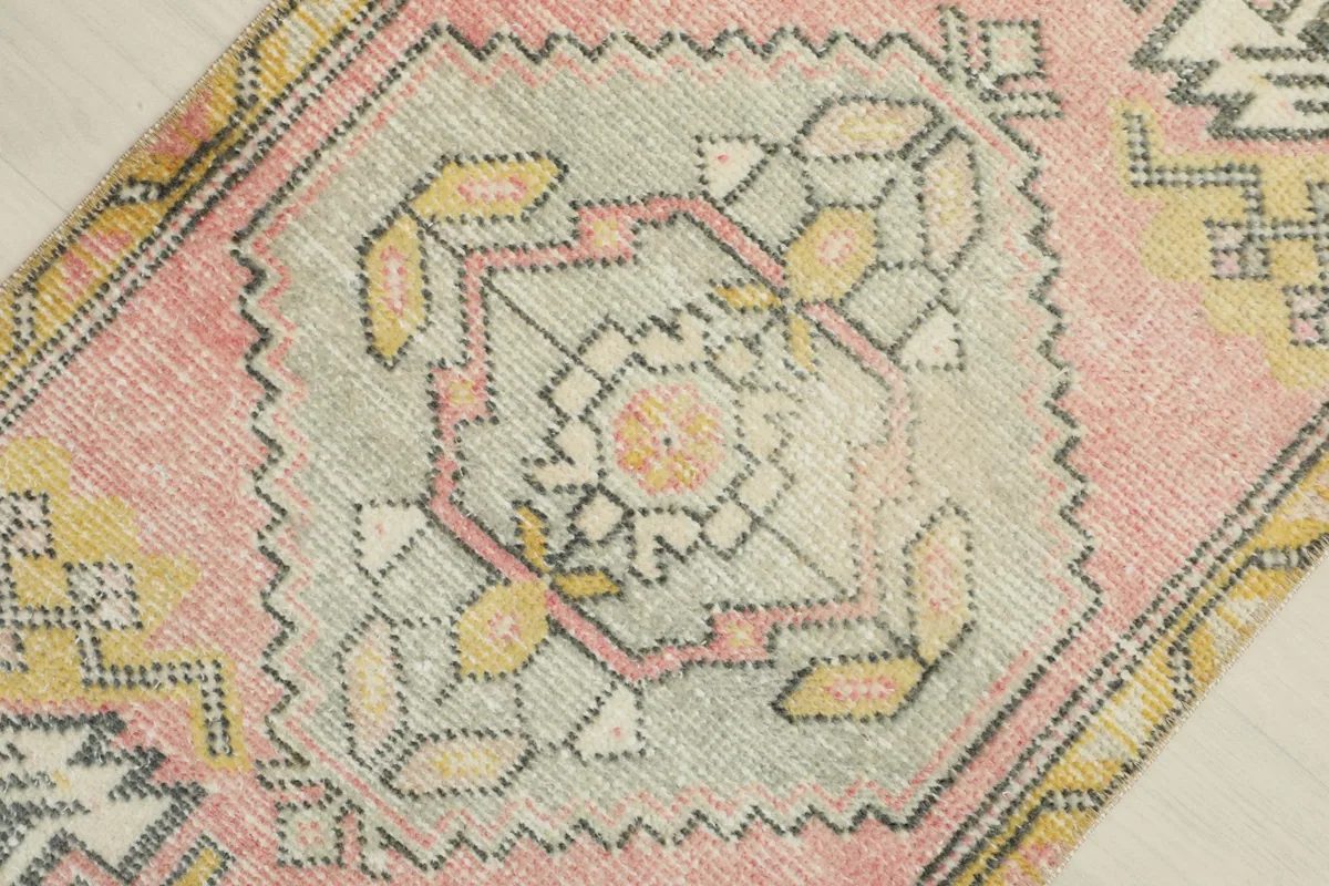 Close-up of the central medallion with pink, yellow, and orange accents on a gray field