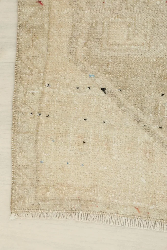 Close-up of a corner, showcasing the hand-knotted construction and natural patina on the ivory and beige wool.