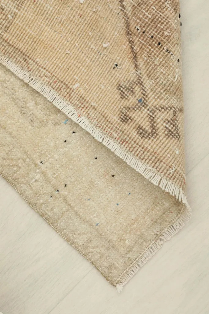 View of the low wool pile and the cotton foundation, demonstrating the rug's construction and thin profile.