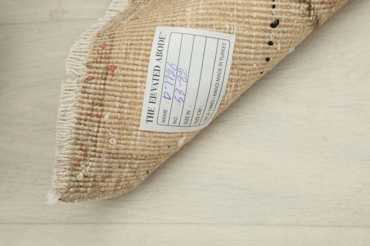 Close-up of the back of the rug with a brand label, showing the hand-knotted cotton foundation.