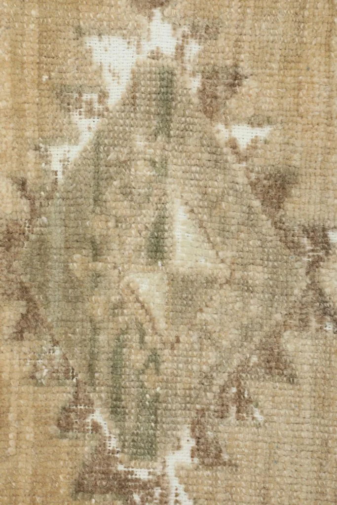 Close-up detail of the central gray and olive geometric pattern and worn pile.