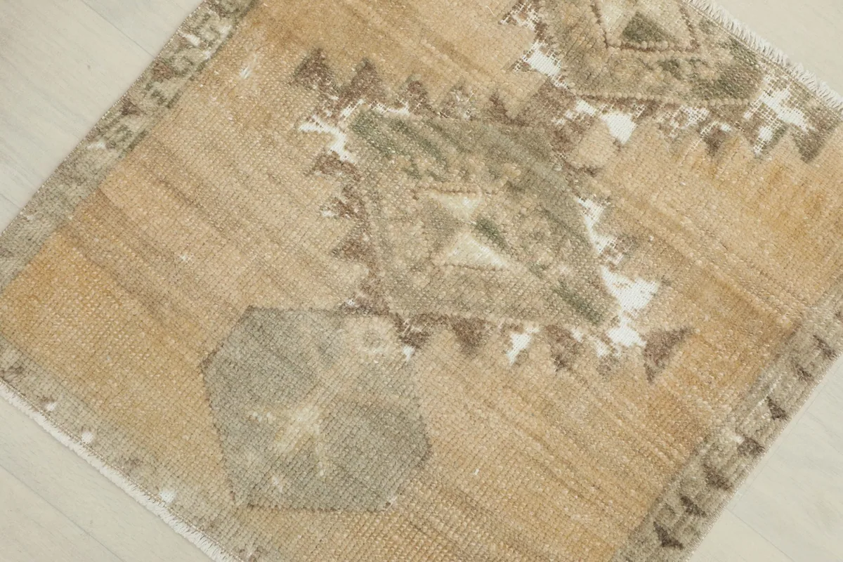 Overhead close-up of the rug's center, highlighting the geometric motif in tan, gray, and olive.