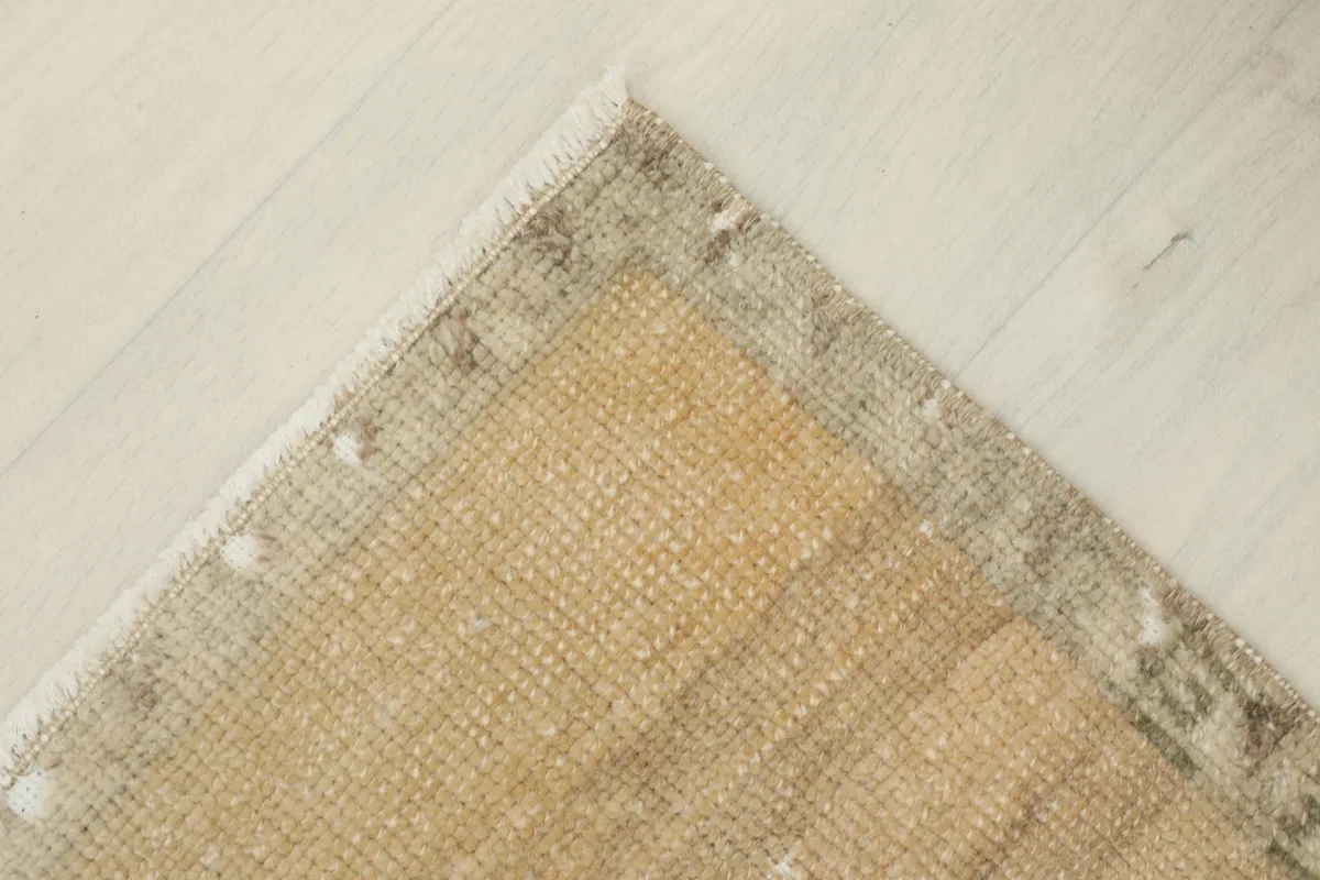 Corner view showing the reverse side of the rug's corner and the cotton foundation.