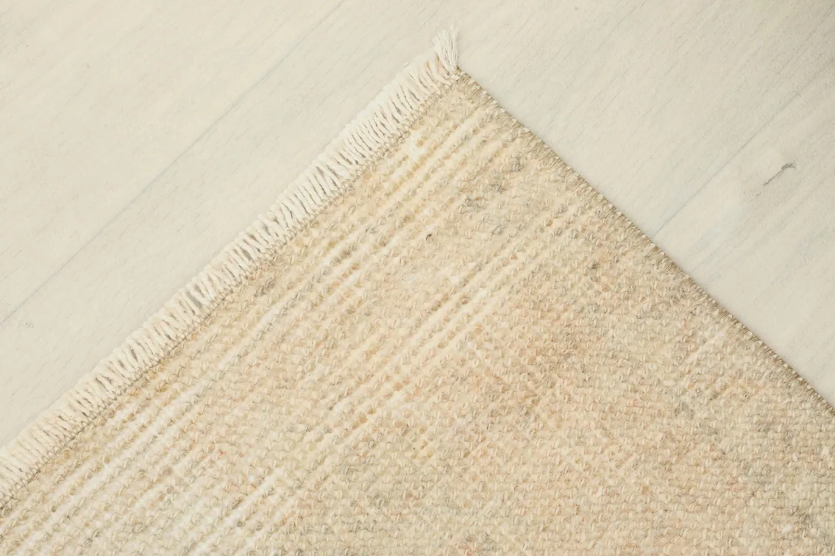 Corner view of the rug, displaying its flat lie on the floor and the clean, short fringe.