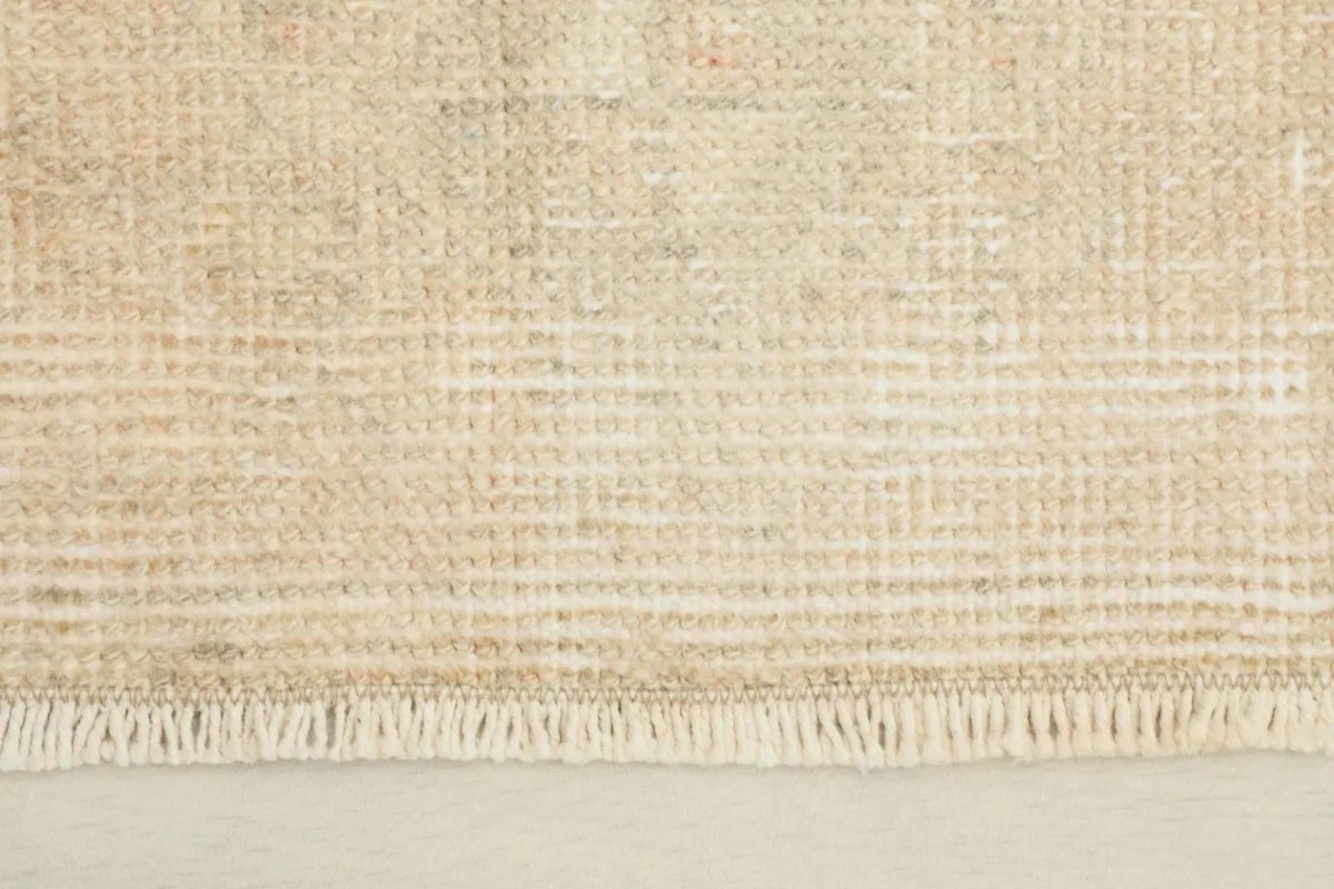 Close-up view of the rug's short fringe and the tightly woven wool pile, showing texture and subtle color variations.