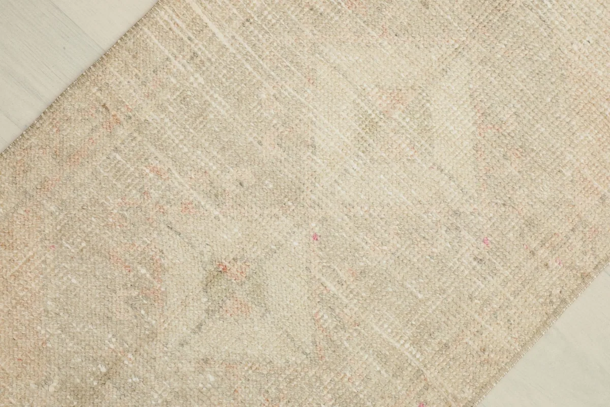 Diagonal close-up of the rug's surface, highlighting the faded geometric patterns and low pile texture.