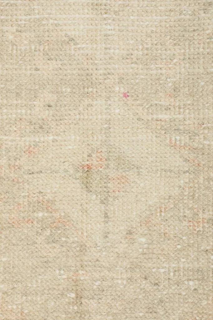 Overhead close-up of the central part of the rug, revealing the subtle tribal motifs in ivory and beige tones.
