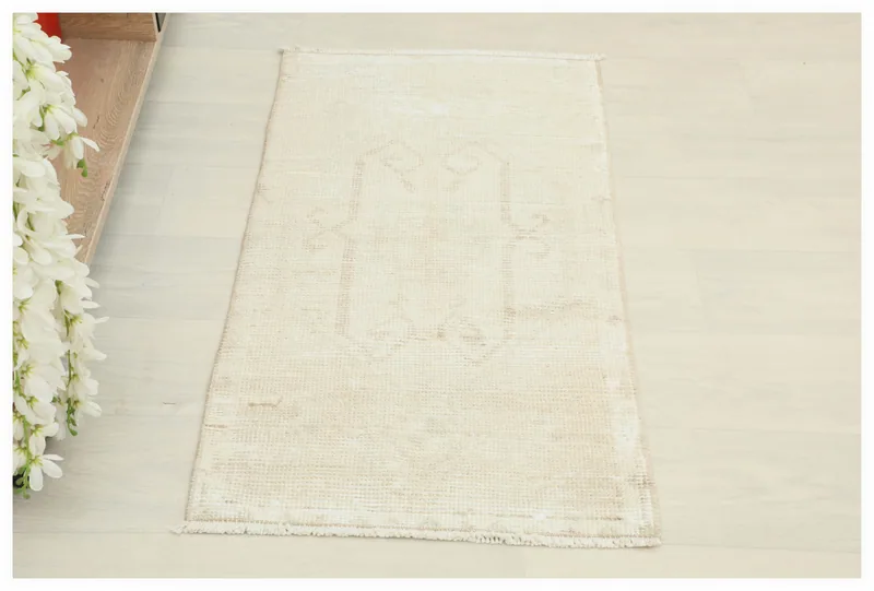 Full top view of the 1'9" x 3'3" ivory and beige vintage Anatolian doormat on a white background.